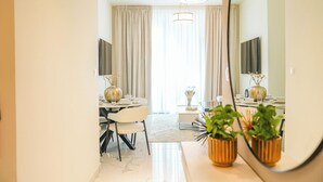 Ett modernt hotellrum med en matplats, en stor spegel och utsikt över vardagsrummet.