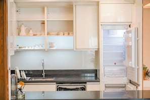 Eine moderne Küche mit weißen Schränken, einem Edelstahl-Spülbecken und einem integrierten Kühlschrank.