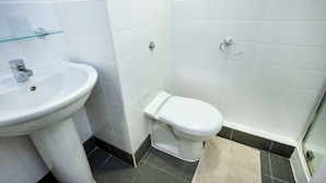A bathroom with a white sink, toilet, and a glass shelf. - Student Only Apollo Works (Coventry)