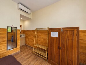 Une pièce dotée d’un plancher en bois, d’une armoire en bois, d’un miroir et d’un climatiseur fixé au mur.