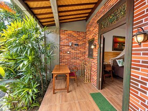 A room with a brick wall, a wooden table, and a green mat. - Pondok Juli Canggu (Canggu)