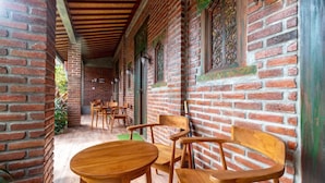 A covered outdoor seating area with brick walls and wooden furniture.