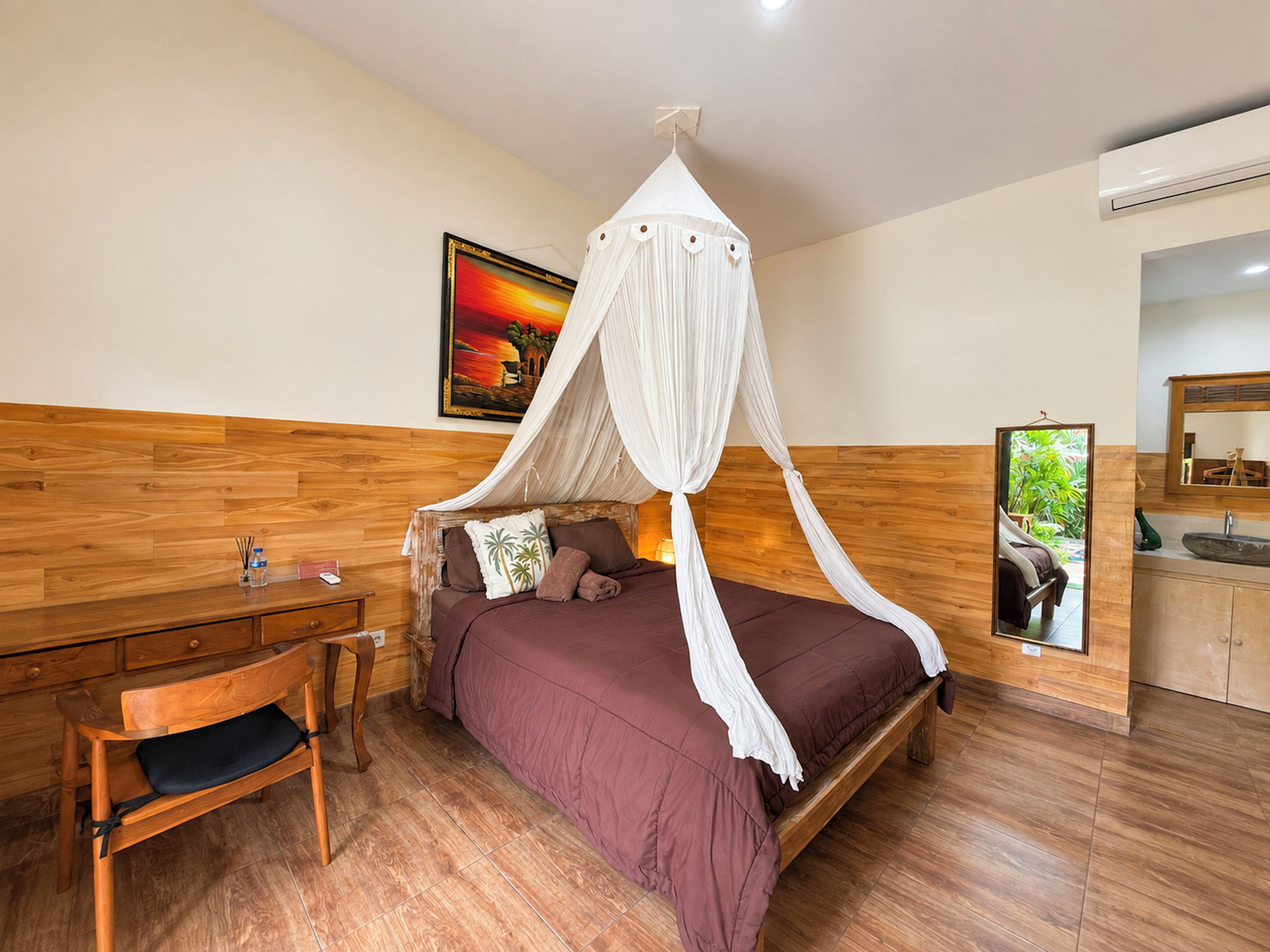 A bedroom with a bed, wooden headboard, bedside table, chair, and a nightstand.