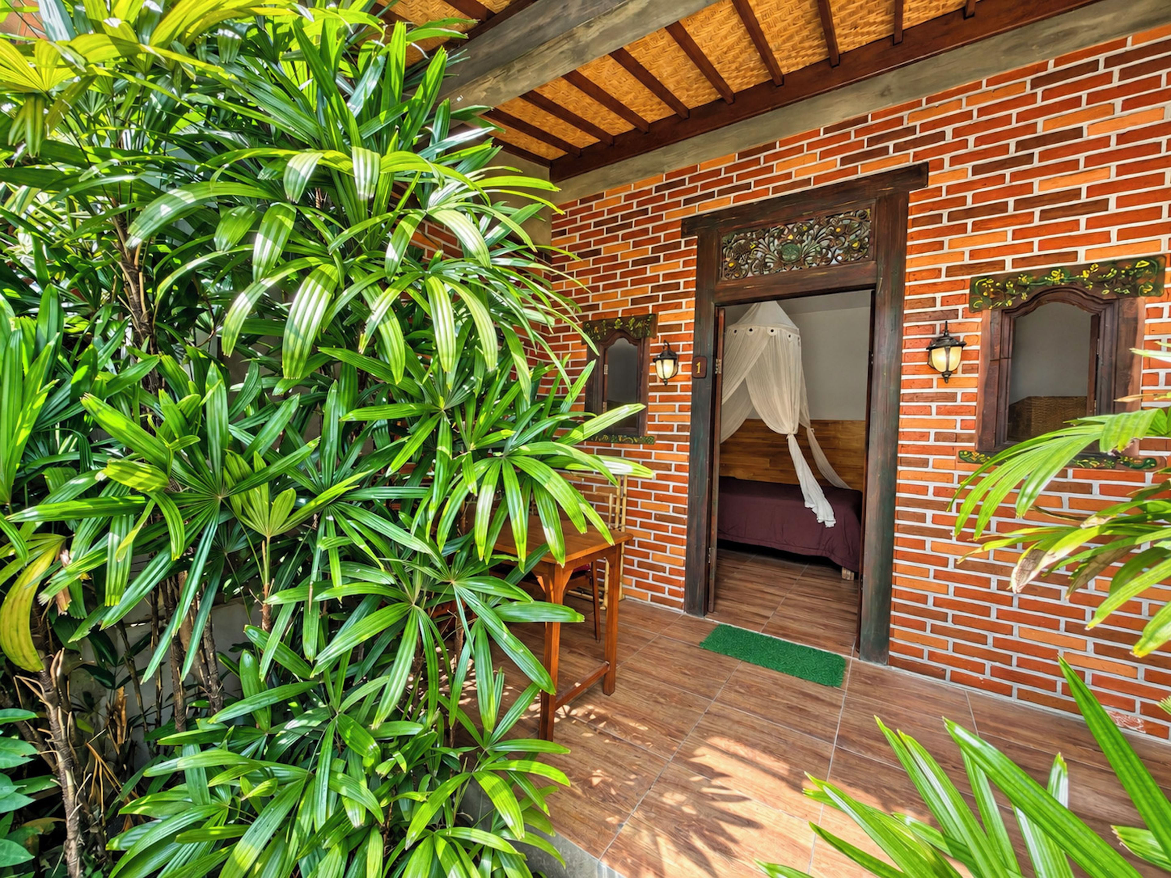 A room with a brick wall, a bed with a canopy, and a wooden door.