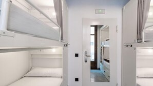 A narrow corridor with bunk beds on either side, a door at the end, and a mirror reflecting the corridor. - Black Swan Hostel Granada (Granada)