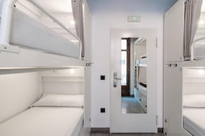 A narrow corridor with bunk beds on either side, a door at the end, and a mirror reflecting the corridor. - Black Swan Hostel Granada (Granada)