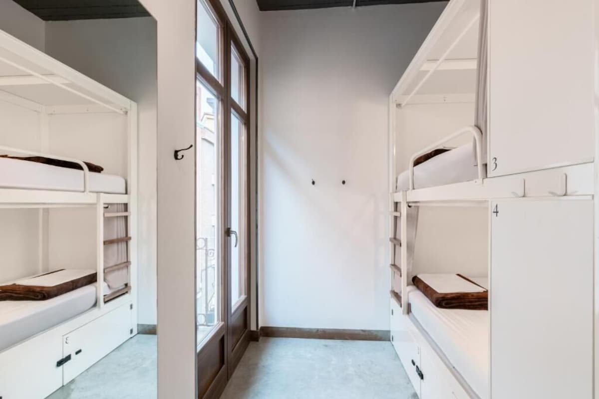A room with bunk beds, a window, and a door.