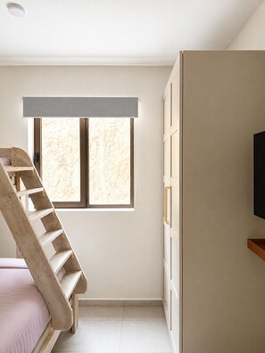 Une chambre avec une échelle en bois, une fenêtre et un téléviseur fixé au mur.