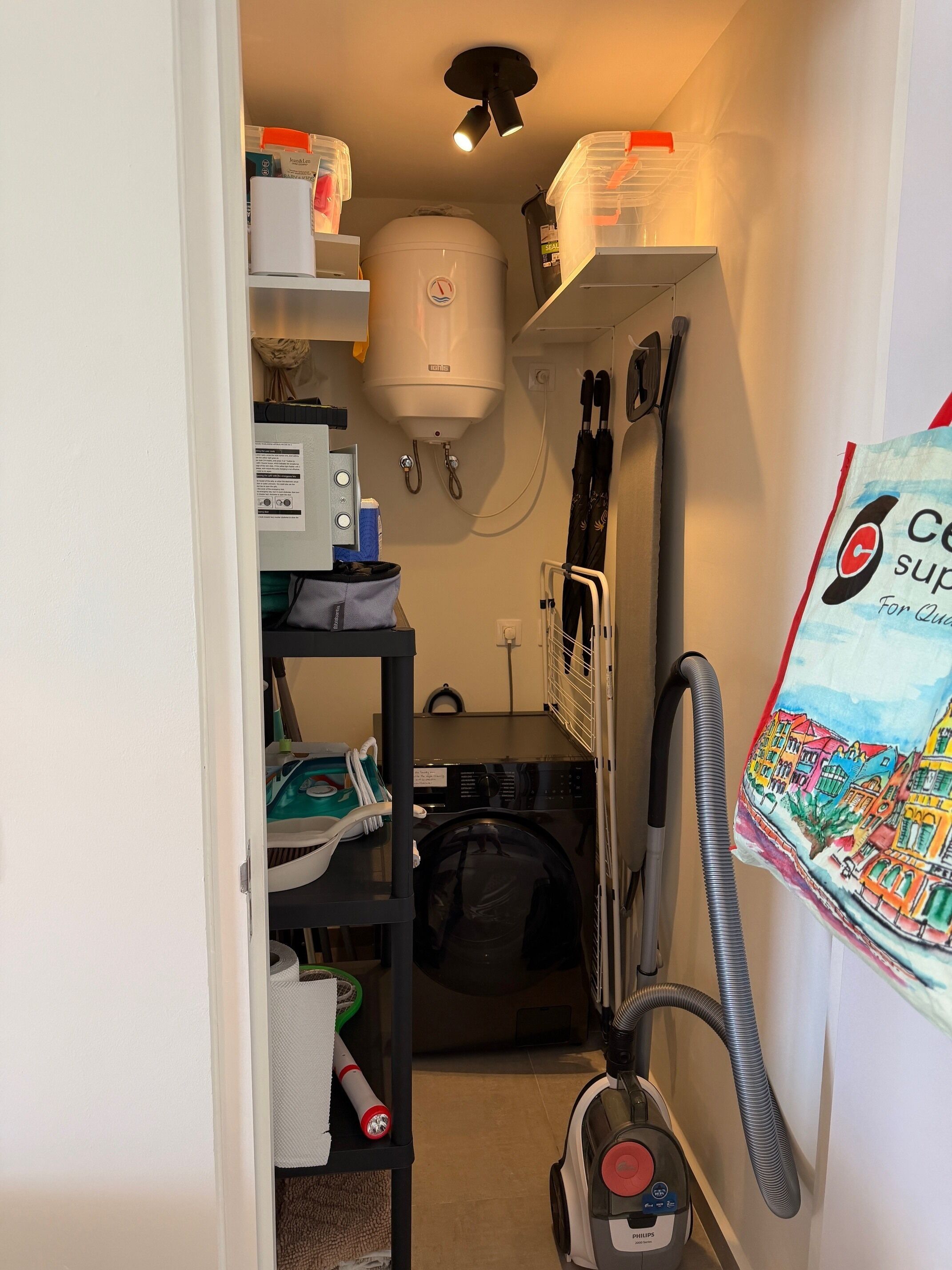A laundry room with a washing machine, a vacuum cleaner, and a water heater.