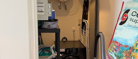 A laundry room with a washing machine, a vacuum cleaner, and a water heater.
