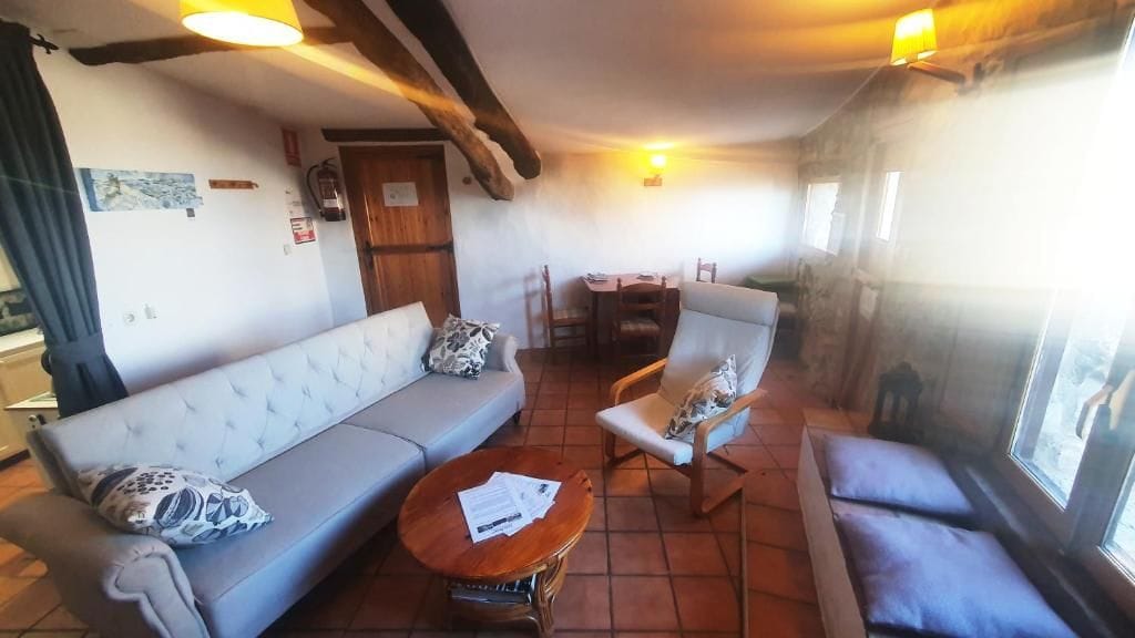 Ein gemütliches Wohnzimmer mit einer Couch, Sesseln, einem kleinen Tisch und einem Fenster mit Blick.