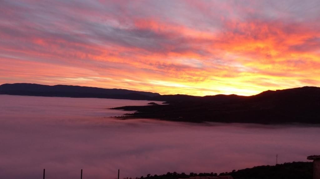 A sunset over a body of water with a distant landmass.