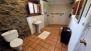 A bathroom with a stone wall, a toilet, a sink, and a shower.