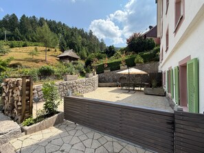 Un patio con piso de piedra, cercado con valla de madera y una mesa con sillas.