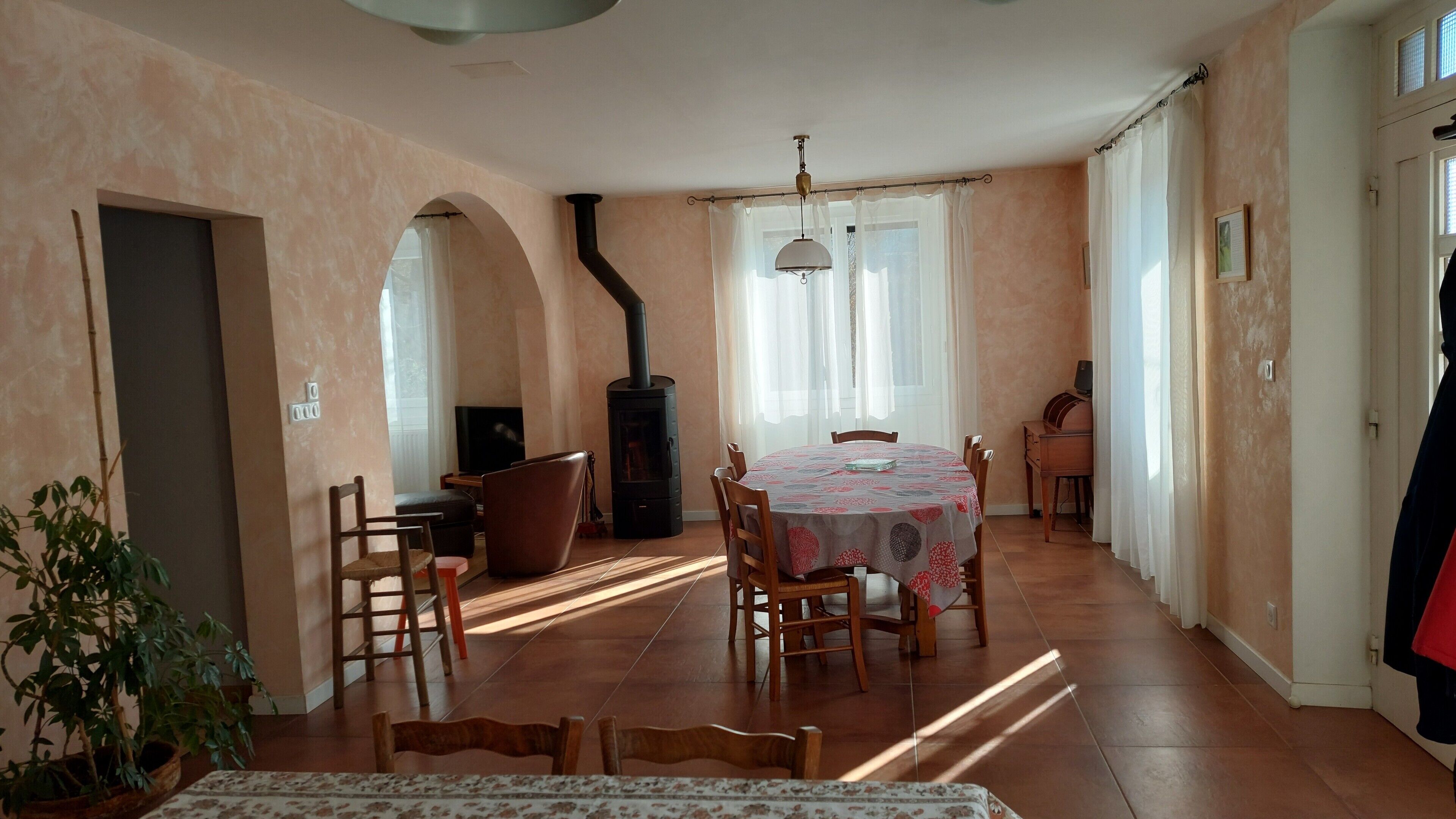 A dining area with a round table, chairs, a sofa, a TV, and a fireplace.