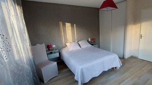 Ein Schlafzimmer mit einem Bett, Nachttischen, einem Sessel, einem Kleiderschrank und einer roten Lampe.