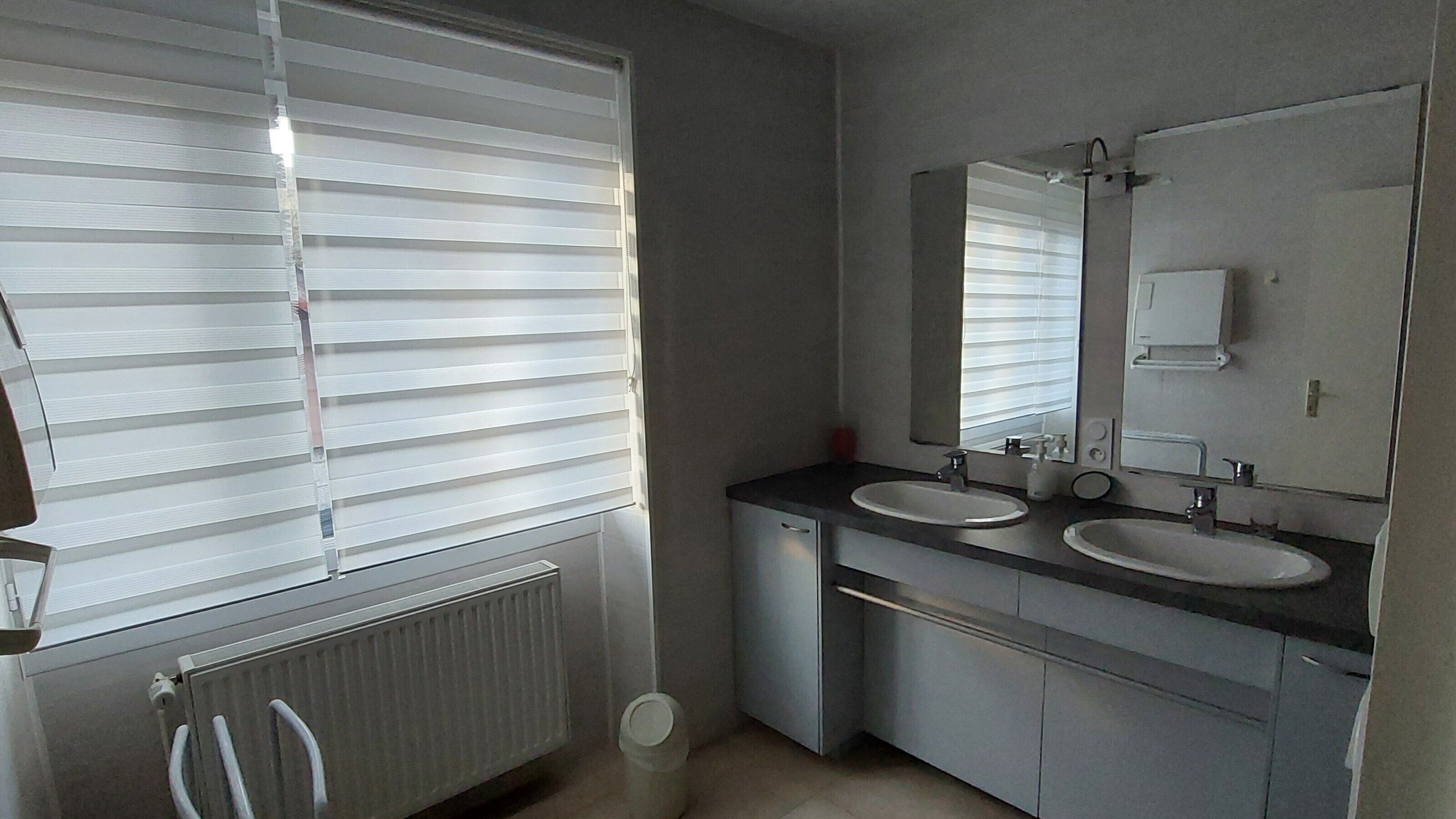 Ein Badezimmer mit zwei Waschbecken, einem Spiegel und einer Heizung.