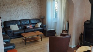 Ein Wohnzimmer mit schwarzem Ledersofa, einem Holztisch und einem Kamin.
