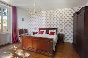 Un dormitorio con cama de madera, candelabro, armario y papel tapiz estampado.