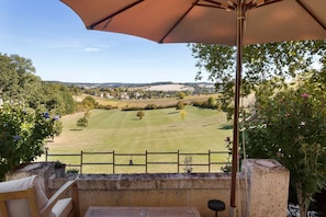 Un patio con mesa y sillas, con vistas a un paisaje rural con campos y árboles.