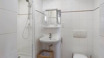 Een badkamer met een douche, wastafel en toilet.