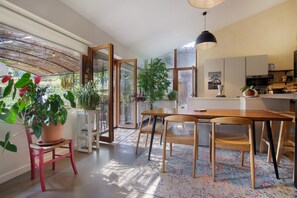 Una cocina moderna con comedor, ventanas amplias y plantas en macetas.