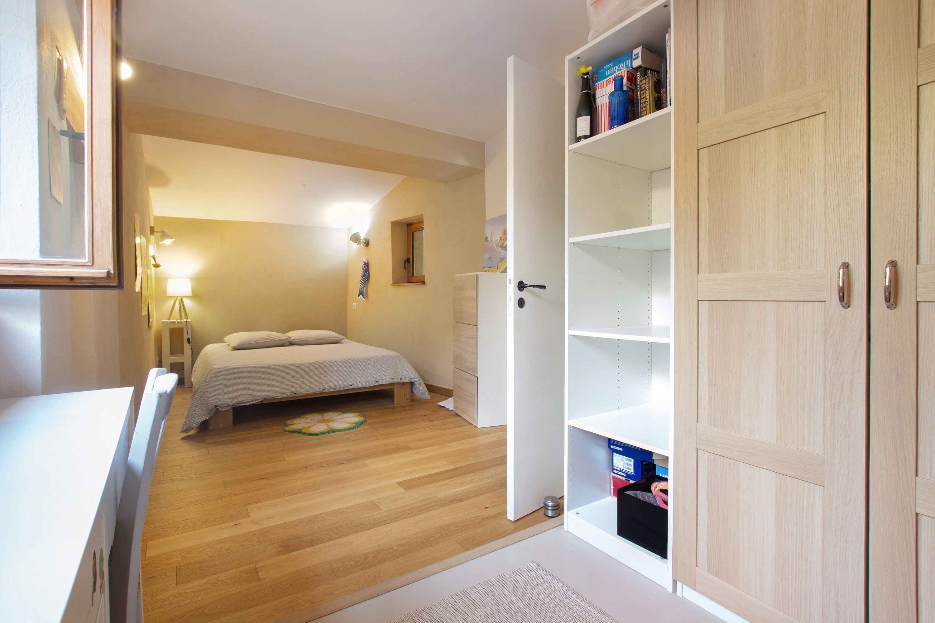 Ein Schlafzimmer mit Bett, Nachttisch, Lampe und Kleiderschrank.