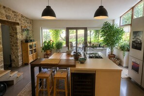 A modern kitchen with a central island, wooden cabinets, and pendant lighting.