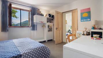 Een slaapkamer met een bed, een kledingkast, een bureau en een raam met gordijnen.
