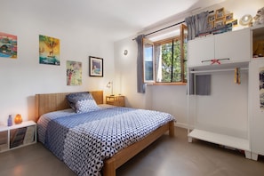 Un dormitorio con cama, mesita de noche, lámpara y armario.