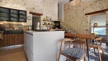 Una cucina moderna con isola centrale, sedie in legno e un muro in pietra.