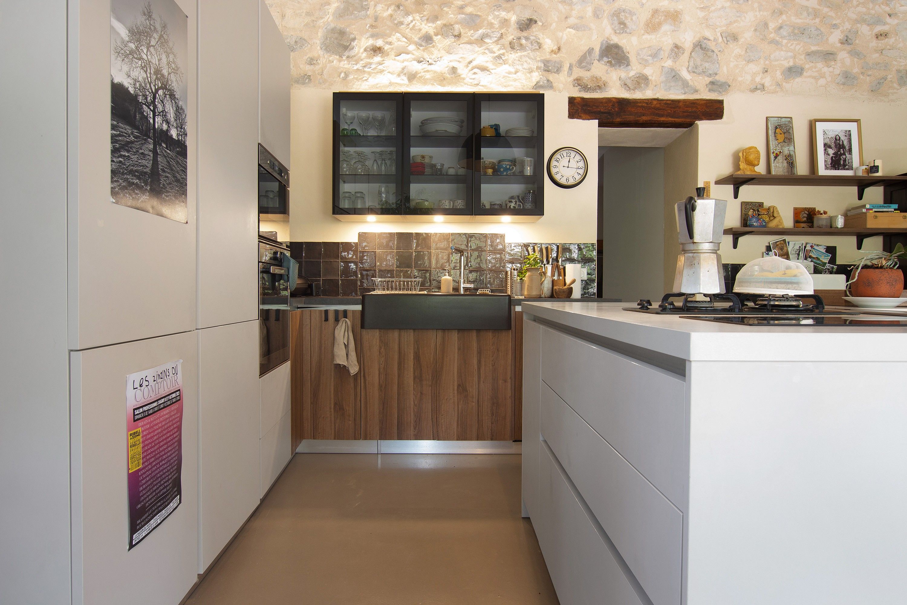 A compact kitchen with a stone wall, wooden cabinets, and a built-in oven.