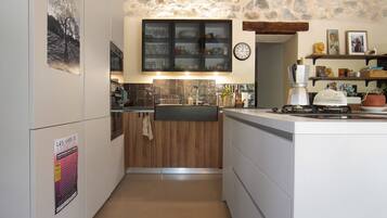 A compact kitchen with a stone wall, wooden cabinets, and a built-in oven.