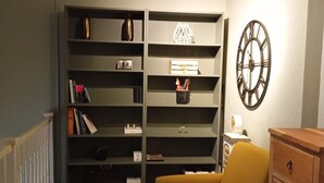 A room with a bookshelf, a clock, a chair, and a dresser.