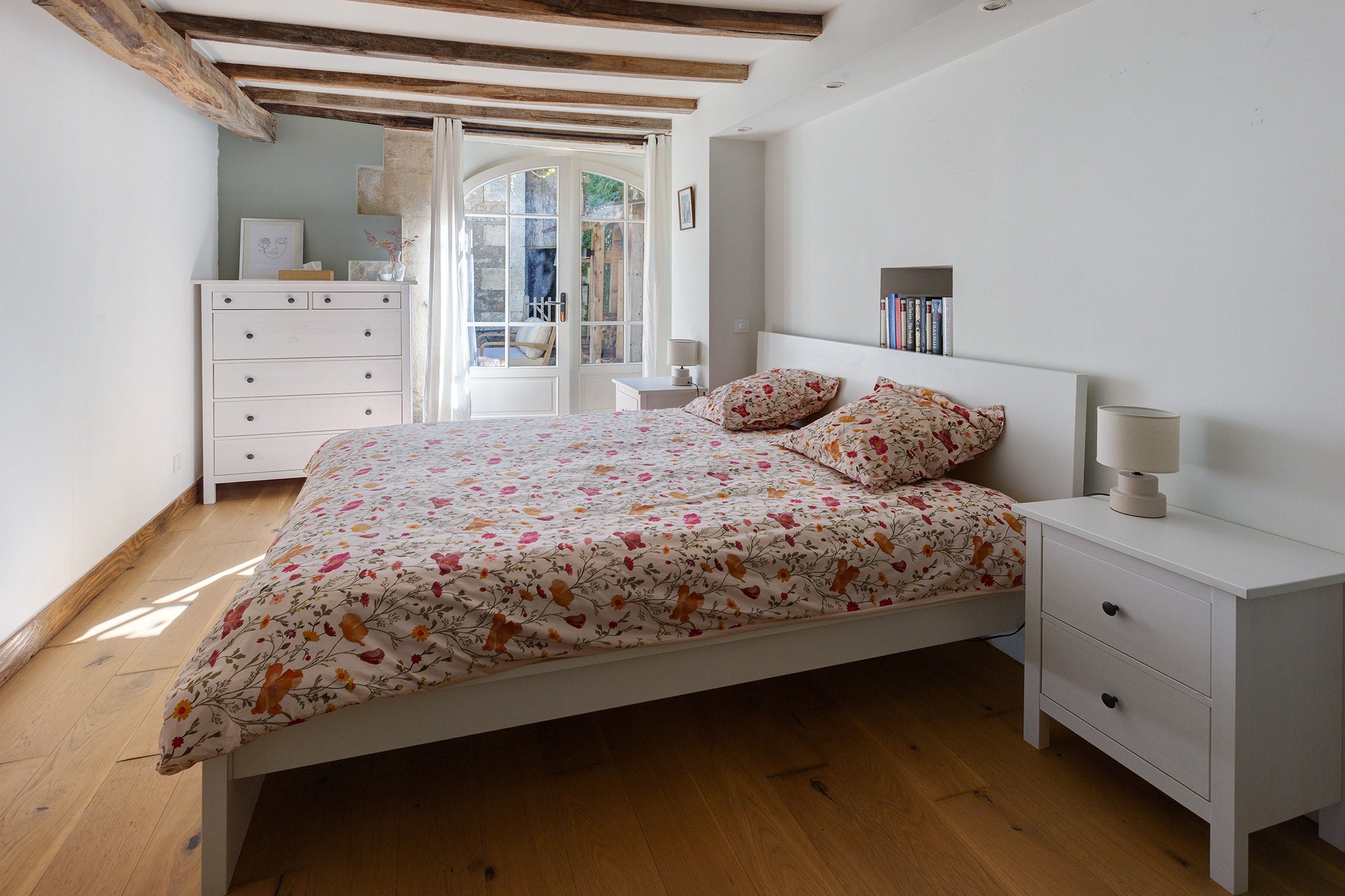 A bedroom with a bed, bedside tables, a dresser, and a window with curtains.