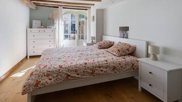 A bedroom with a bed, bedside tables, a dresser, and a window with curtains.