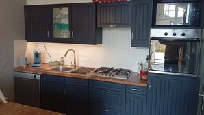 A kitchen with dark cabinets, a stove, an oven, and a sink.