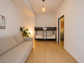 A room with a sofa, bunk beds, a potted plant, and a hanging light fixture.