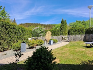 Ein gepflegter Garten mit befestigtem Weg, Holzzaun und Bänken.