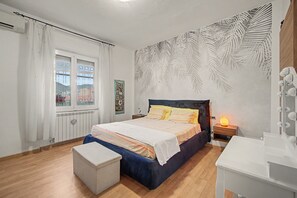 Una camera da letto con un letto, un comodino, una cassettiera e una finestra con tende.