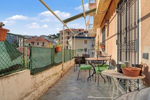 Una terrazza con tavolo e sedie, un recinto verde e piante in vaso.