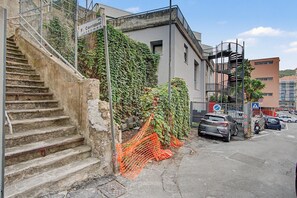 Gradi que porten a un edifici, amb un senyal que indica una zona d'aparcament.
