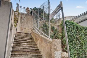 Un escalier en béton mène à un bâtiment entouré d’une clôture métallique et sur lequel est apposée une enseigne indiquant un lieu.