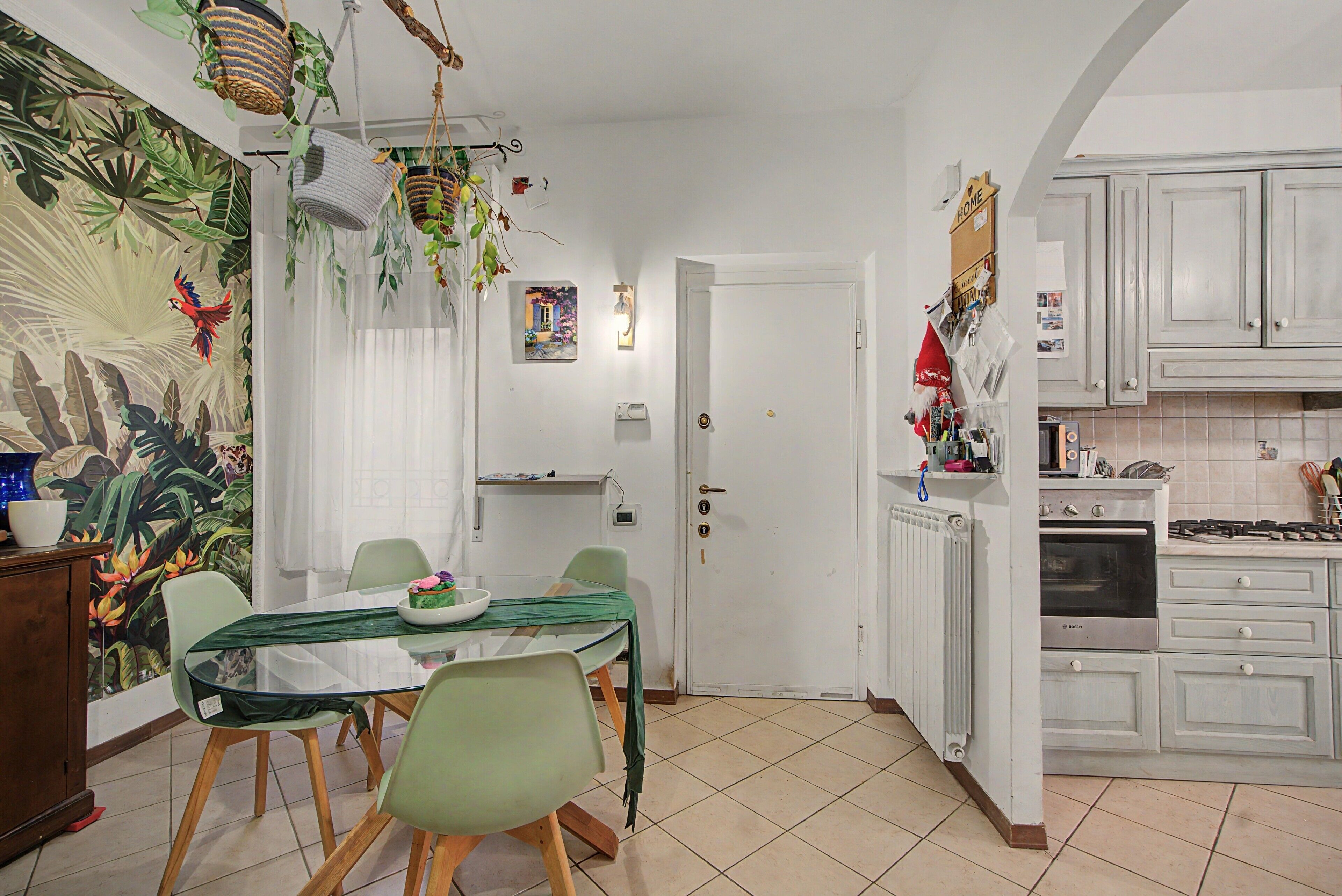Un comedor con una mesa, sillas y un mural tropical en la pared.