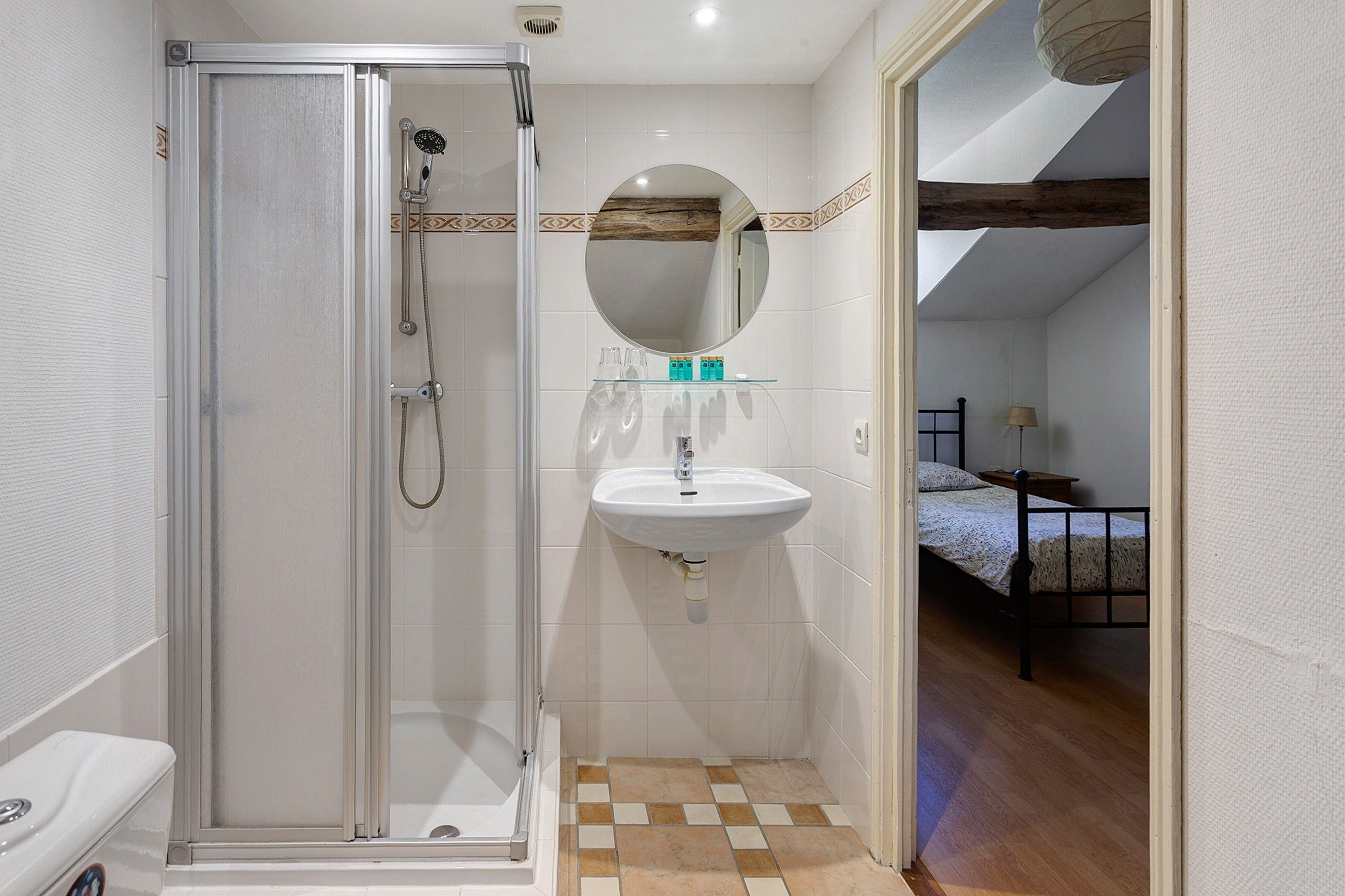 A bathroom with a glass-enclosed shower, a sink, and a mirror.