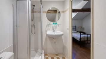 A bathroom with a glass-enclosed shower, a sink, and a mirror.