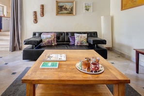 Una sala de estar con una mesa de centro de madera, un sofá con cojines decorativos y un cuadro en la pared.
