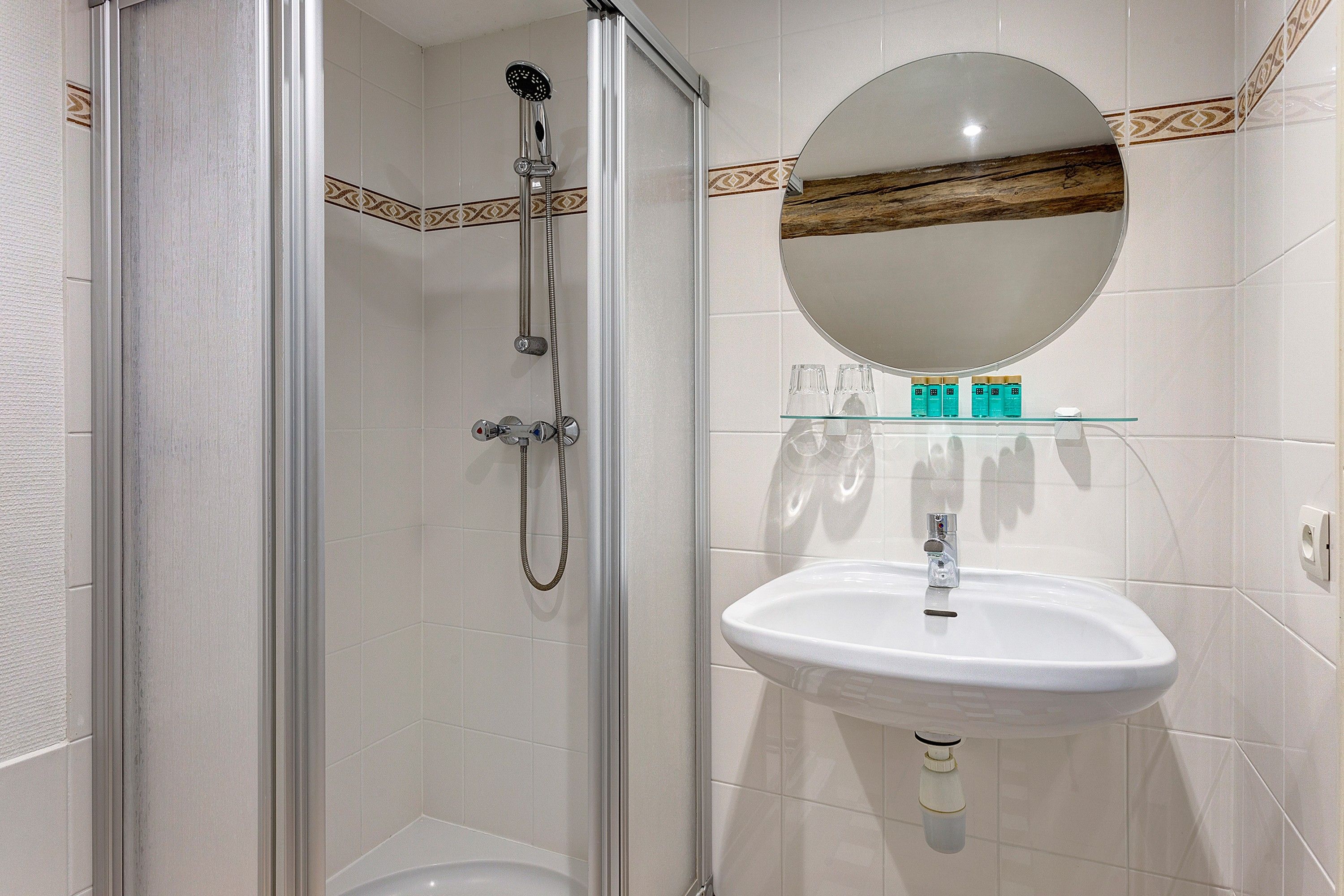 A bathroom with a glass-enclosed shower, a white sink, and a mirror above it.