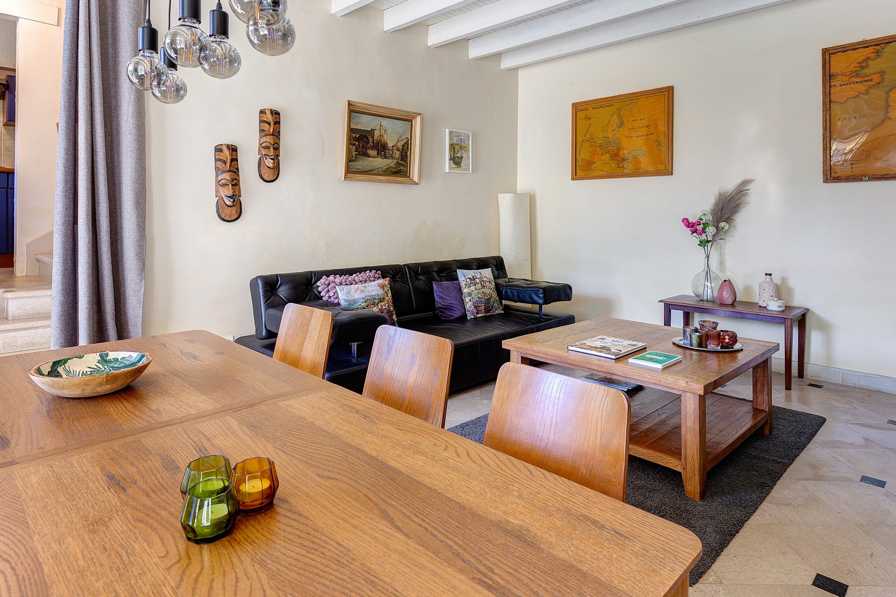 Una sala moderna con una mesa de comedor de madera, un sofá de cuero y varios objetos decorativos.