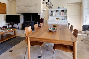 A spacious dining area with a long wooden table, surrounded by chairs, and a fireplace.